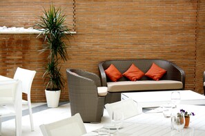 A patio area with wicker furniture, a white table, and a potted plant. - Domus Australia (Rome)