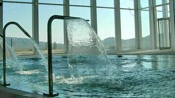 Una piscina con dos chorros de agua y una vista despejada del exterior.