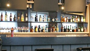 A bar area with shelves of bottles and glasses, a counter, and seating with chairs and tables. - Hotel Bienestar Termas De Vizela (Vizela)