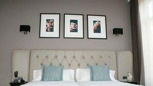 A hotel room with a large bed, two side tables, and three framed pictures on the wall. - Hotel Bienestar Termas De Vizela (Vizela)