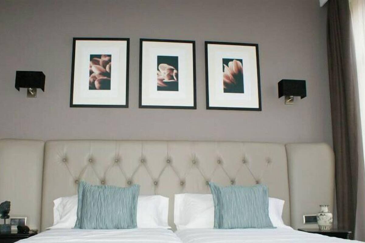 Une chambre d’hôtel avec un grand lit, deux tables de chevet et trois tableaux encadrés accrochés au mur.
