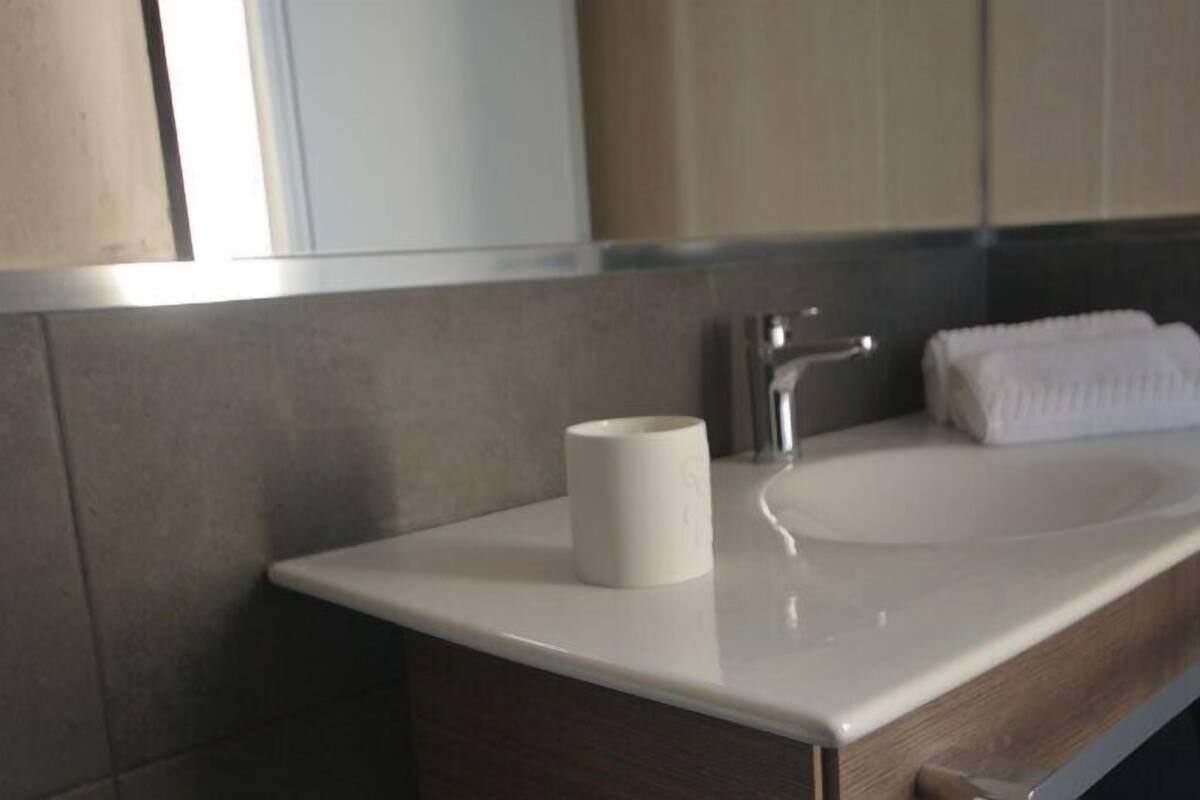Une salle de bain moderne avec un lavabo blanc, une serviette et un rouleau de papier toilette.