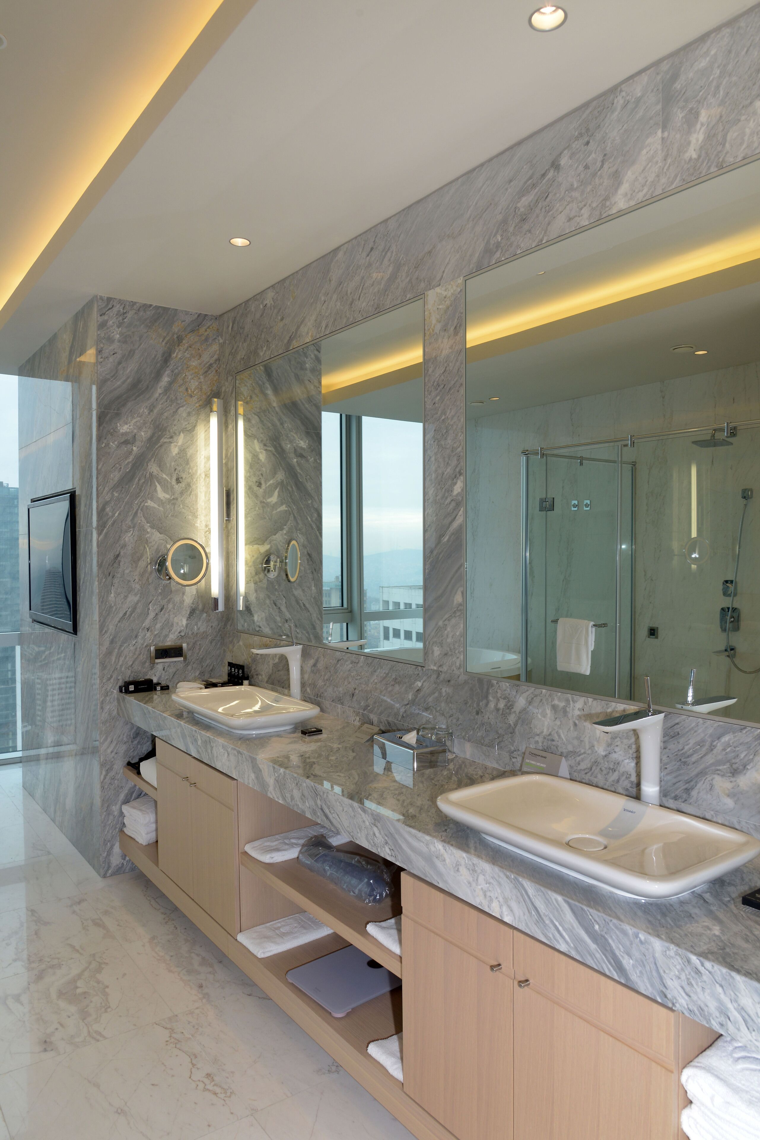 Un baño moderno con dos lavamanos, un espejo grande y una cabina de ducha con paredes de vidrio.
