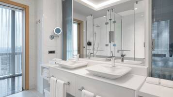 A modern bathroom with two sinks, a large mirror, and a glass shower enclosure.