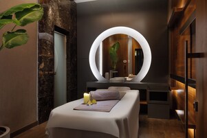 Un spa moderno con una camilla de masaje, un espejo grande y un tocador de madera.