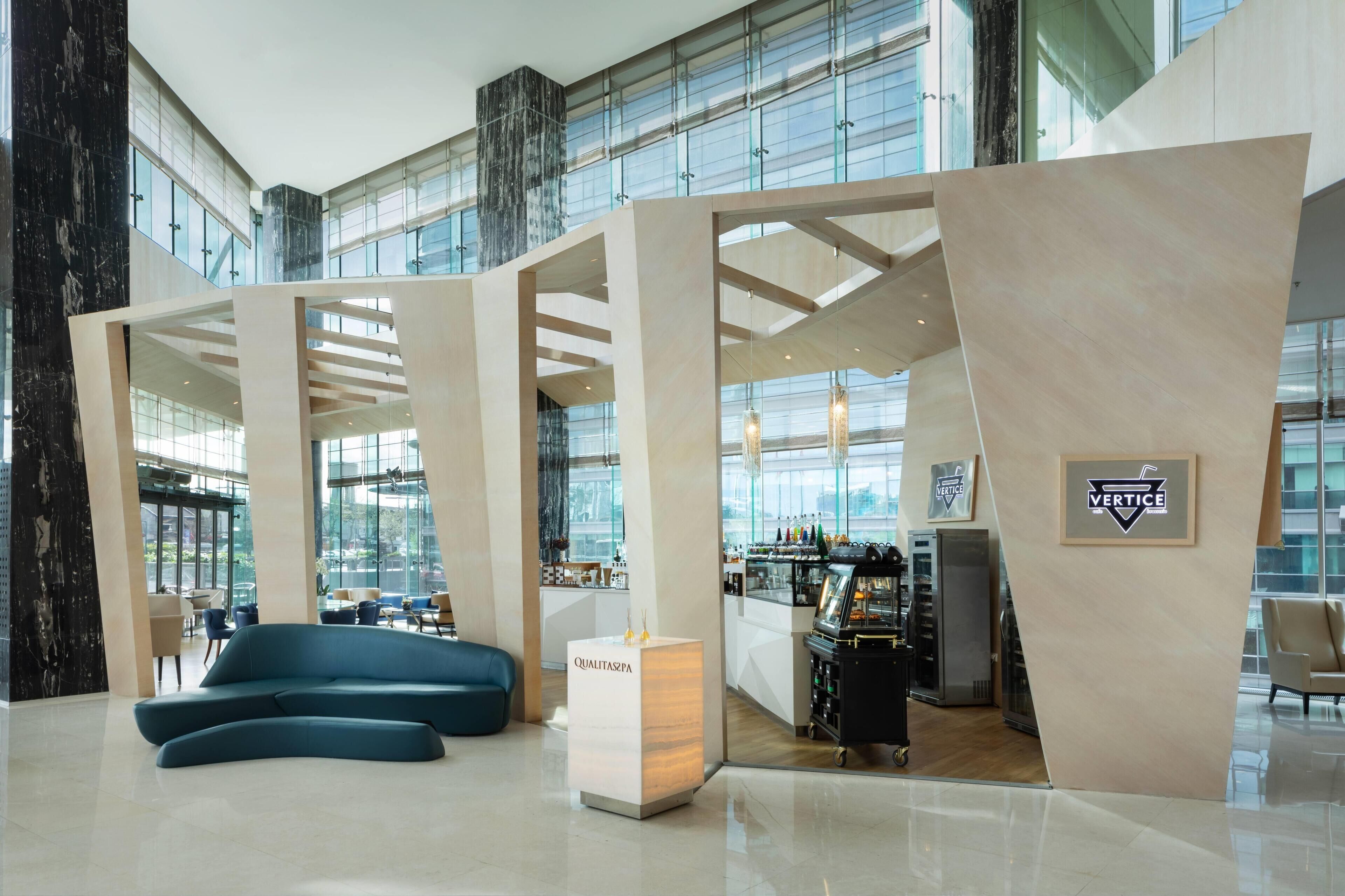 A modern hotel lobby with a seating area, a bar, and a reception desk.