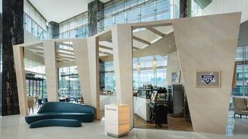 Un moderno vestíbulo de hotel con zona de estar, bar y recepción.