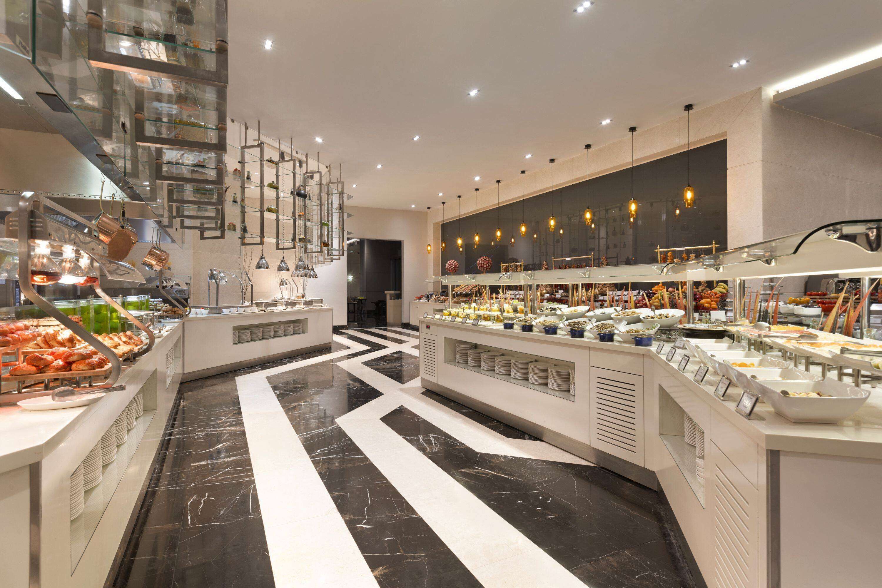 Un buffet proposant une variété de plats, avec différents postes de service et un décor intérieur moderne.