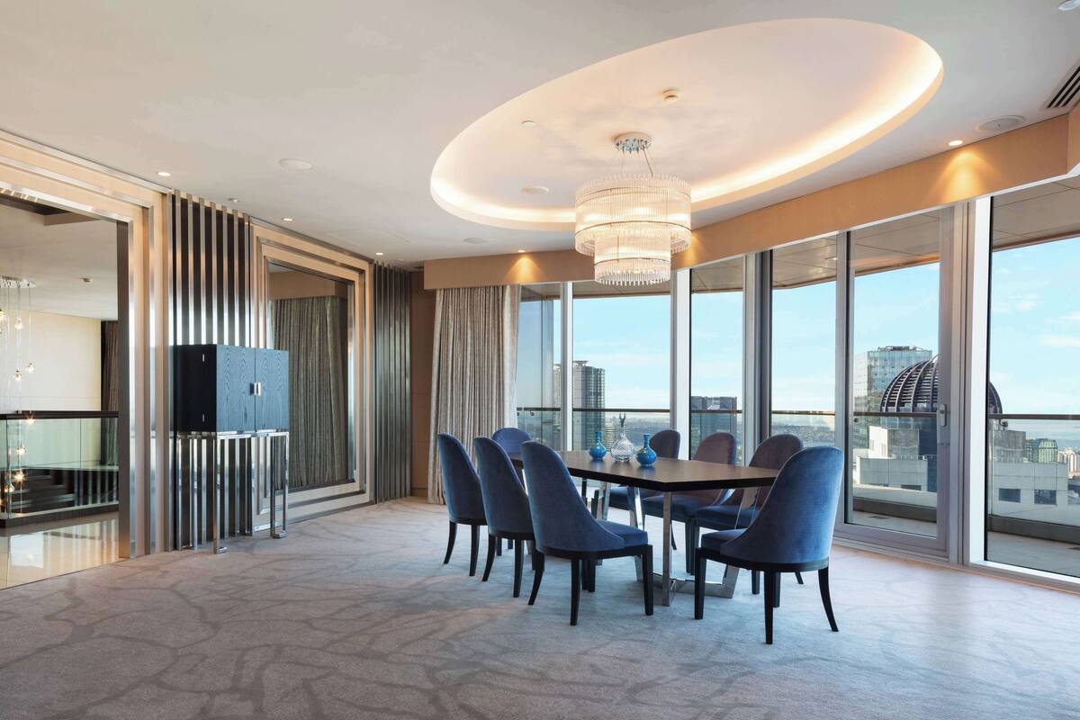 Ein moderner Essbereich mit einer Chandelüster, großen Fenstern und Blick auf die Stadt.