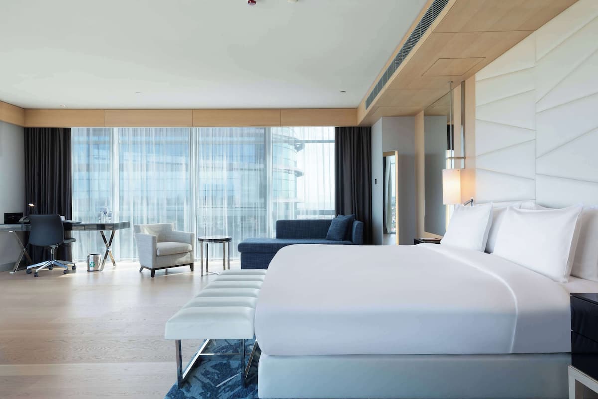 Ein modernes Hotelzimmer mit einem großen Bett, einem Schreibtisch, einem Sessel und einer Couch.