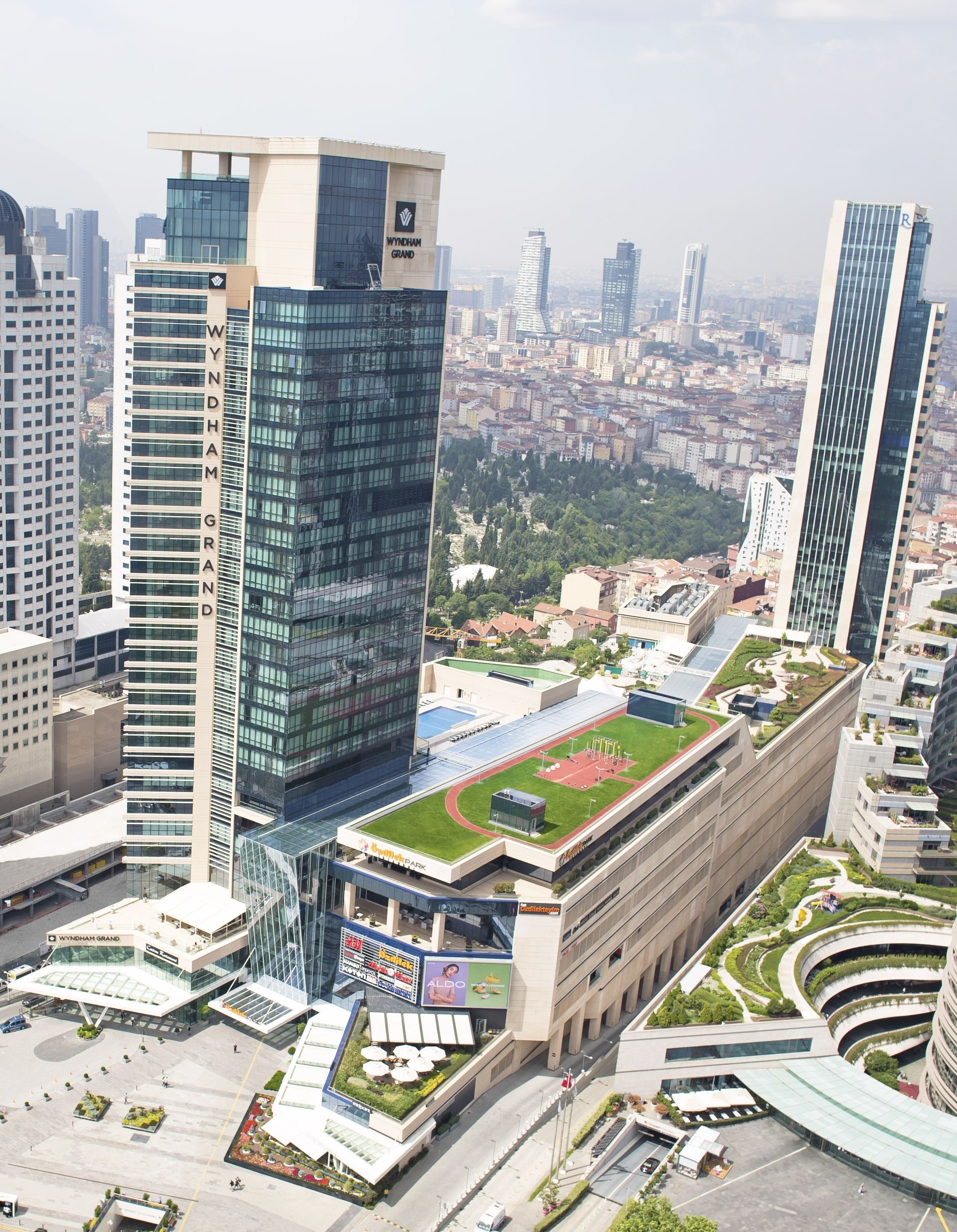 A modern building with a prominent 'Wyndham Grand' sign, surrounded by other high-rise buildings and a green park area.