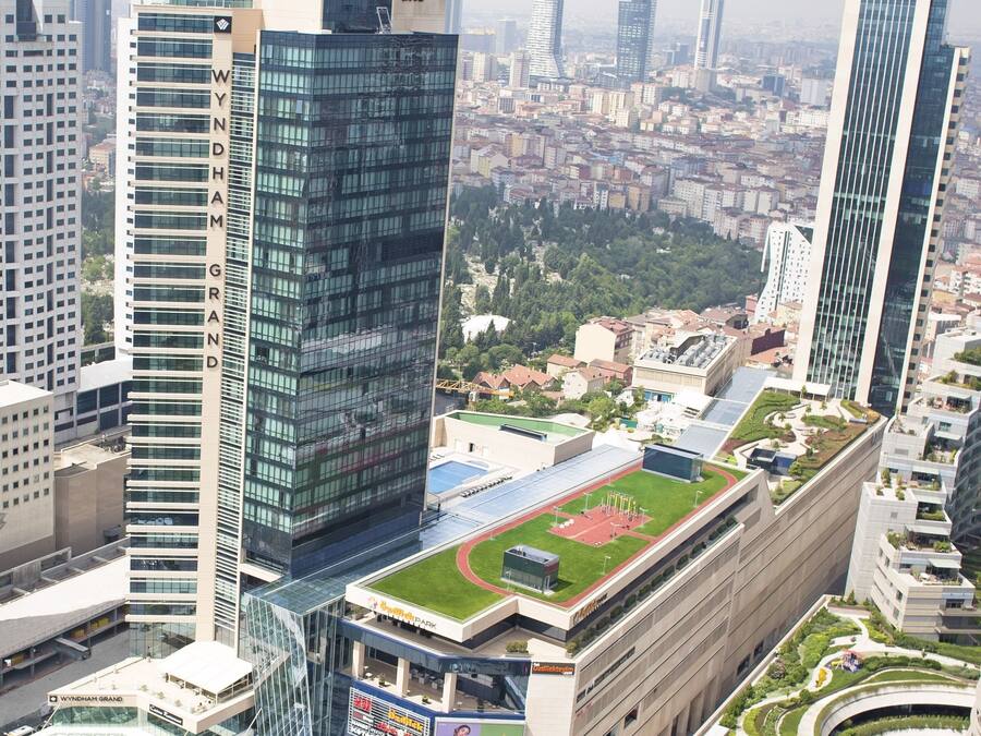 A modern building with a prominent 'Wyndham Grand' sign, surrounded by other high-rise buildings and a green park area.