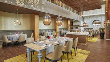 Un restaurante moderno con varias zonas de comedor, techo de madera y lámparas colgantes.