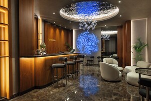 Una hall moderna con zona bar, posti a sedere e una lampada decorativa a soffitto.