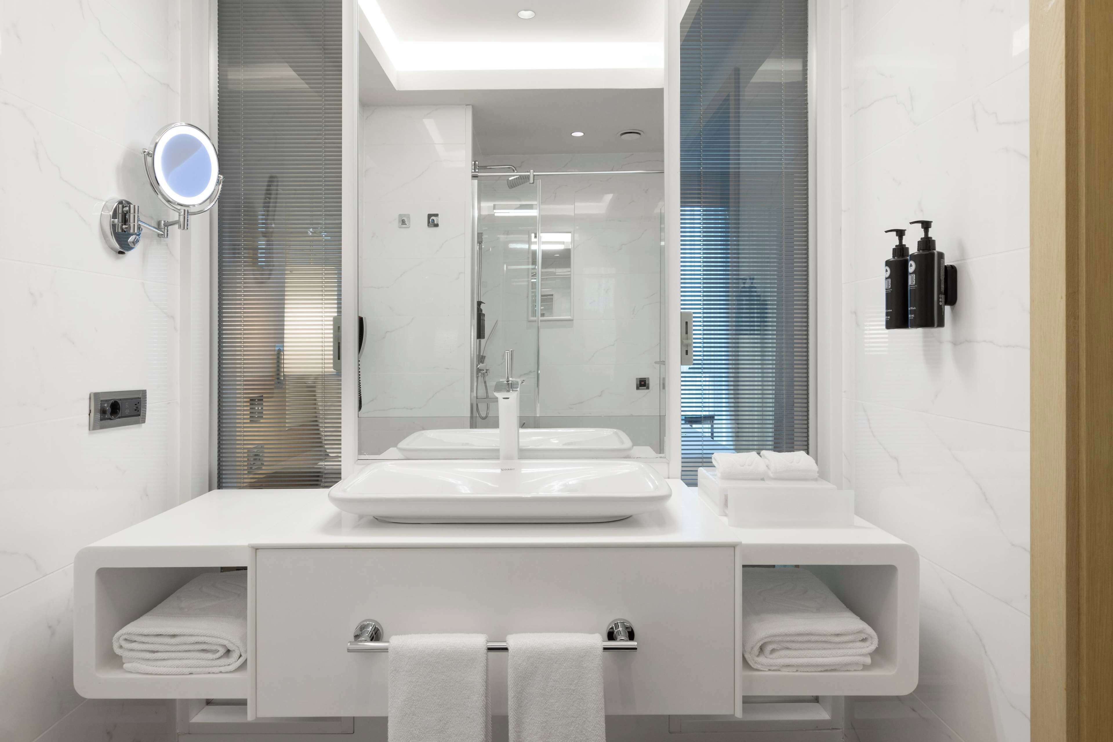 A modern bathroom with a large mirror, two sinks, and a shower.