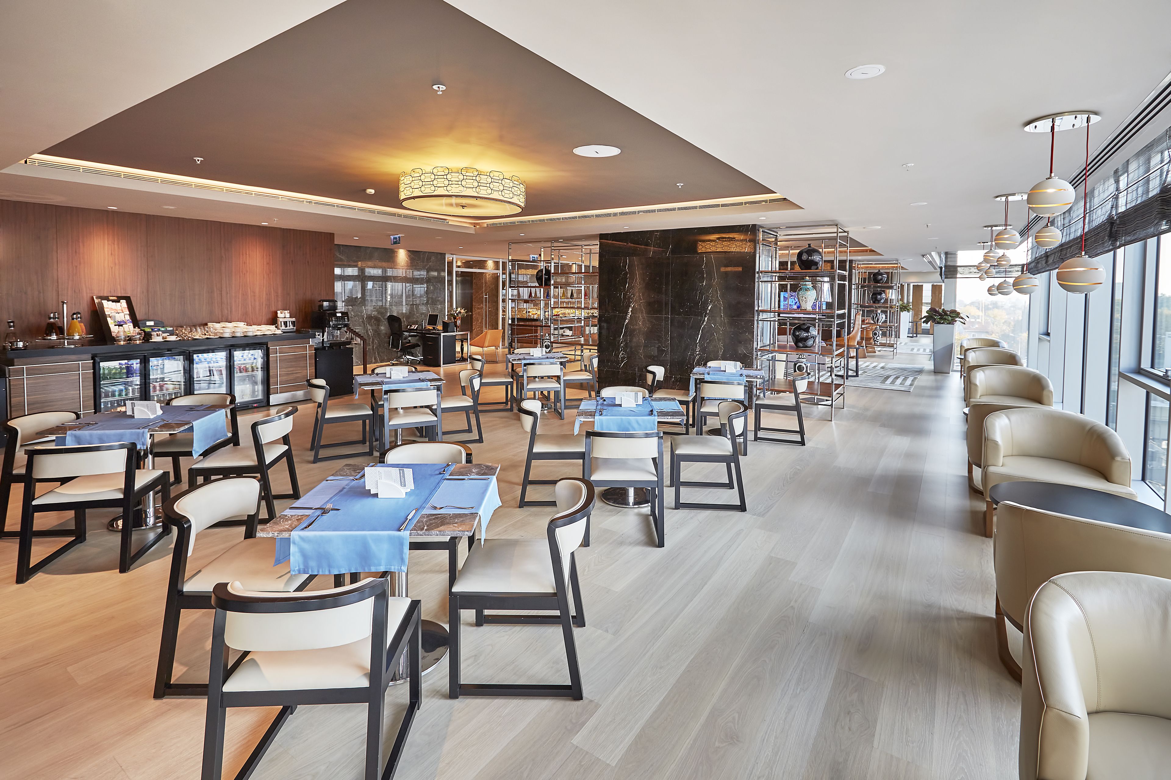 A spacious restaurant with multiple tables and chairs, a bar area, and a large window providing a view.