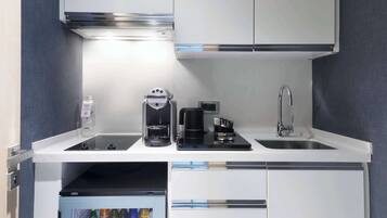 Una cocina compacta con cafetera integrada, un lavamanos y un refrigerador pequeño.