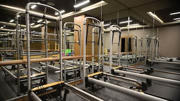 A gym with various exercise equipment, mirrors, and wooden flooring.