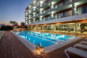 Una piscina al aire libre, sombrillas, sillones reclinables de piscina