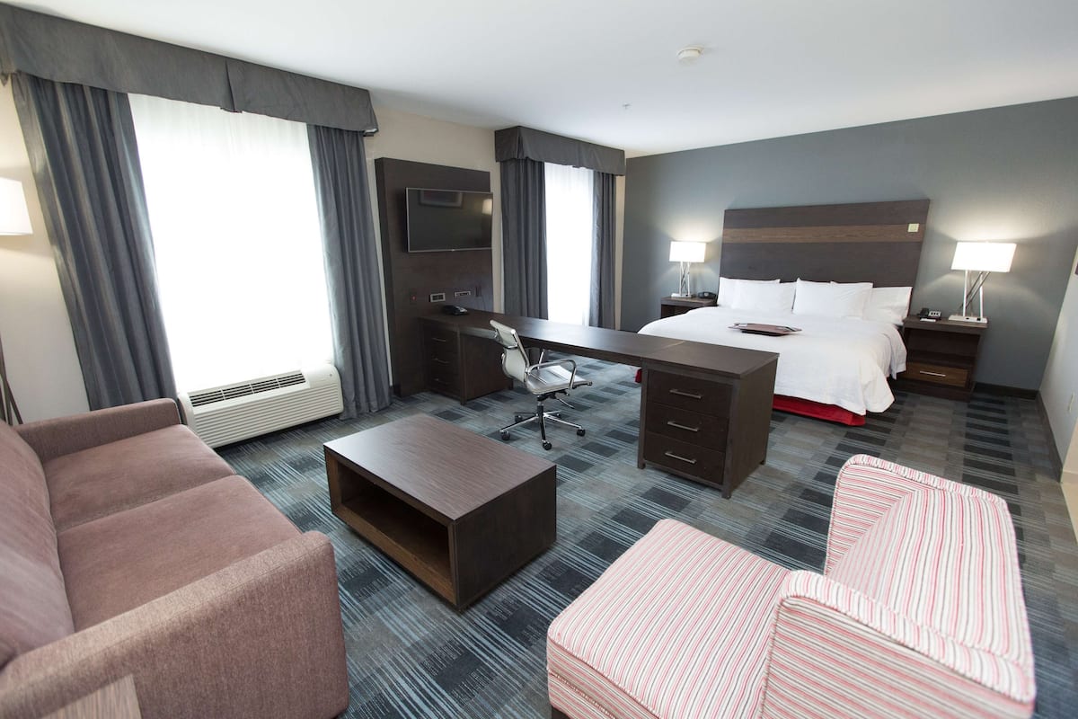 A hotel room with a bed, desk, two chairs, a coffee table, and a TV.