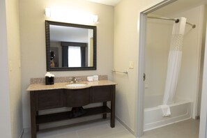 A bathroom with a sink, mirror, and shower. - Hampton Inn & Suites Oklahoma City Airport (Oklahoma City)