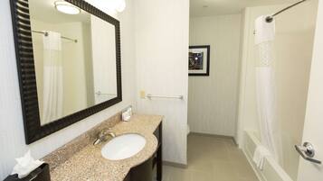 A bathroom with a sink, mirror, and shower.