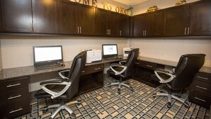 A modern office space with dark wooden cabinets, two computer workstations, and black office chairs. - Hampton Inn & Suites Oklahoma City Airport (Oklahoma City)