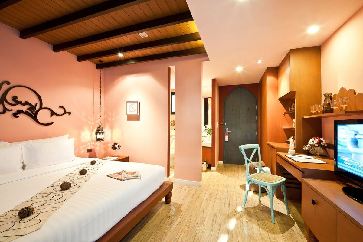 A bedroom with a bed, bedside table, lamp, and a television.