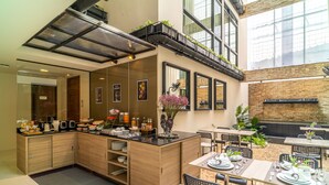 A modern restaurant with a bar area, wooden cabinets, and a seating area with tables and chairs. - Amber Boutique Silom Hotel (Bangkok)
