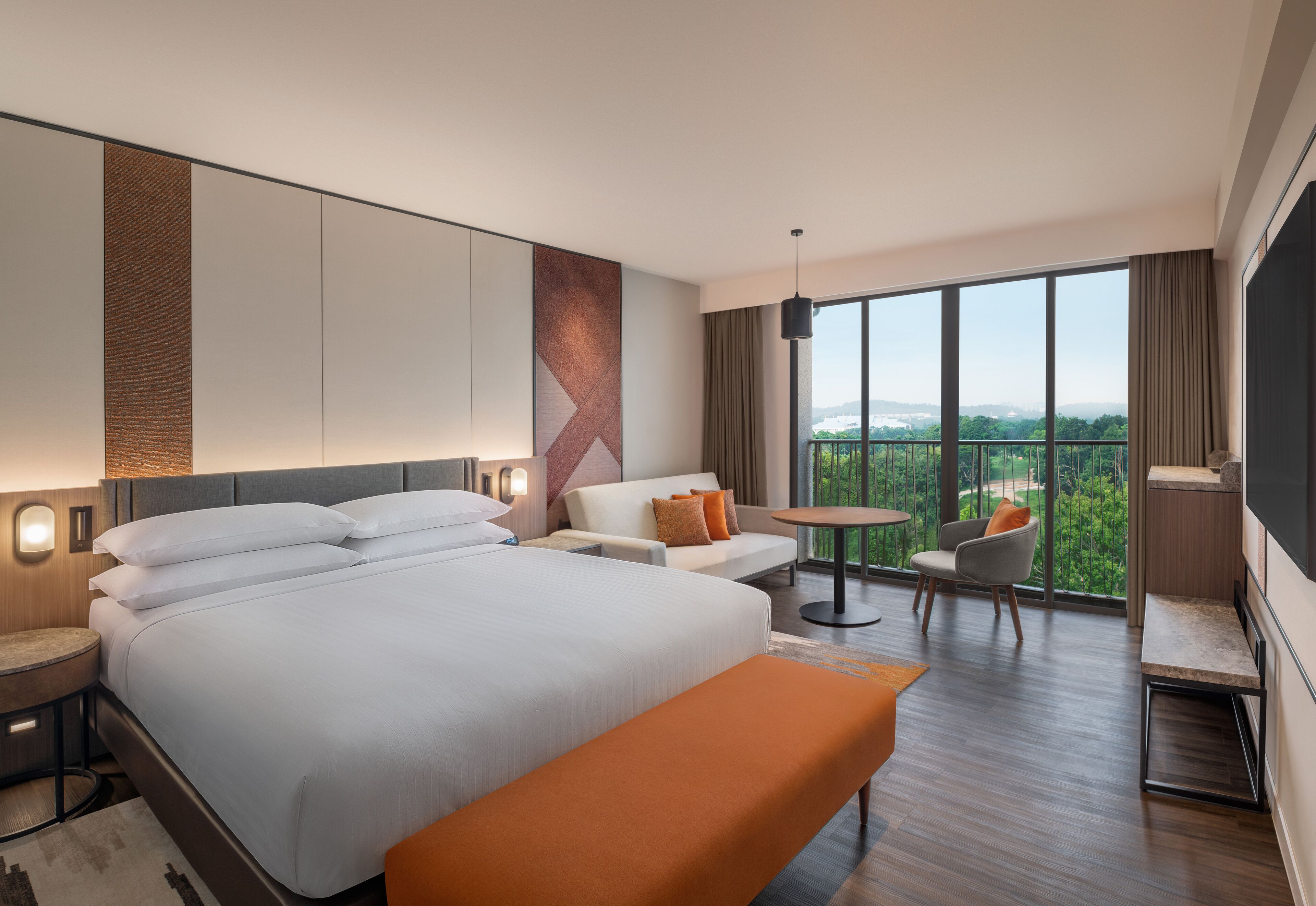 Una habitación de hotel moderna con una cama grande, un área de descanso con una mesa y un balcón con vistas.