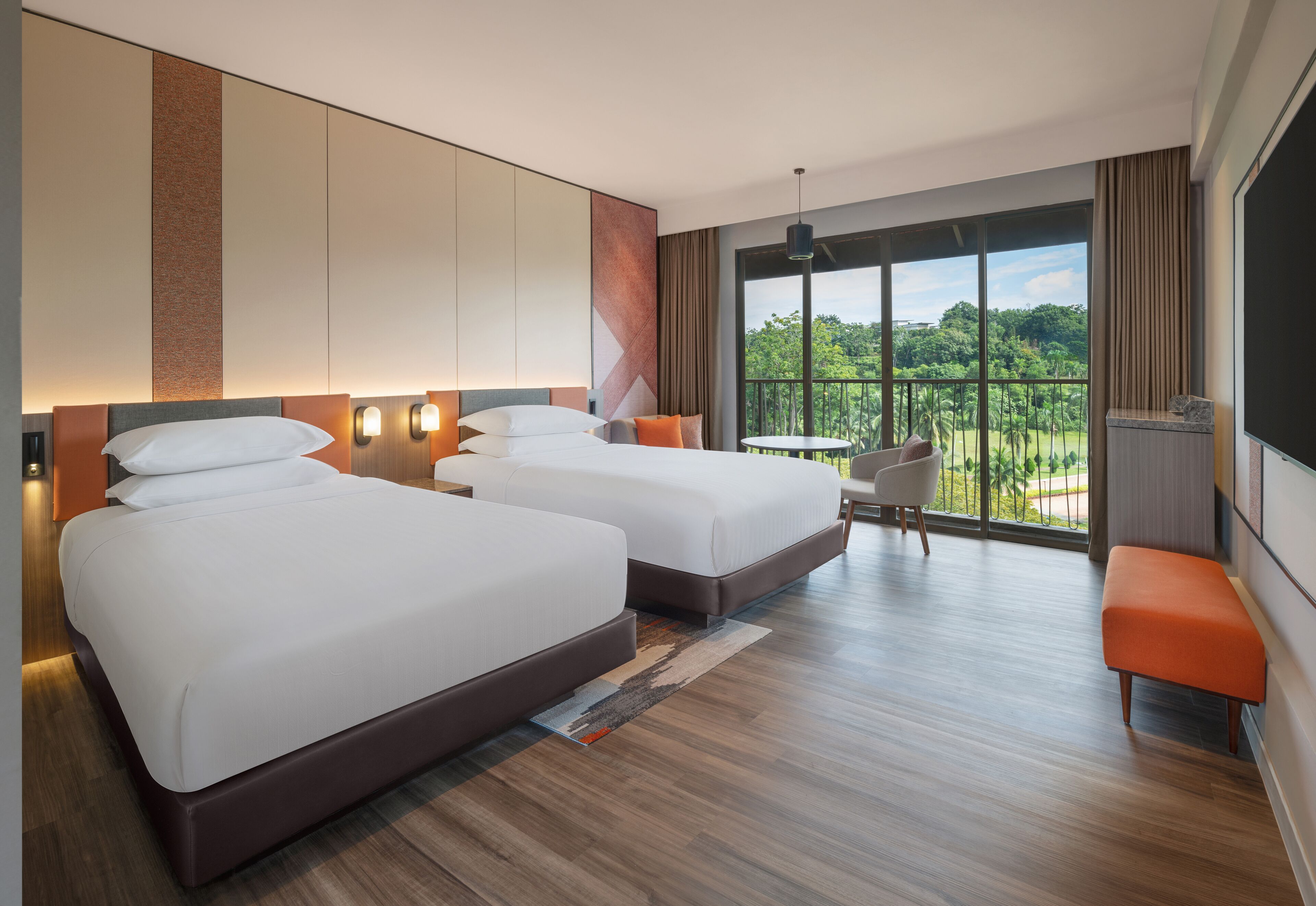 A hotel room with two beds, a balcony with a view, and a small table with chairs.