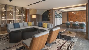 A modern living room with a sectional sofa, a coffee table, and a bookshelf. - Palm Garden Hotel, Putrajaya, a Tribute Portfolio Hotel (Serdang)