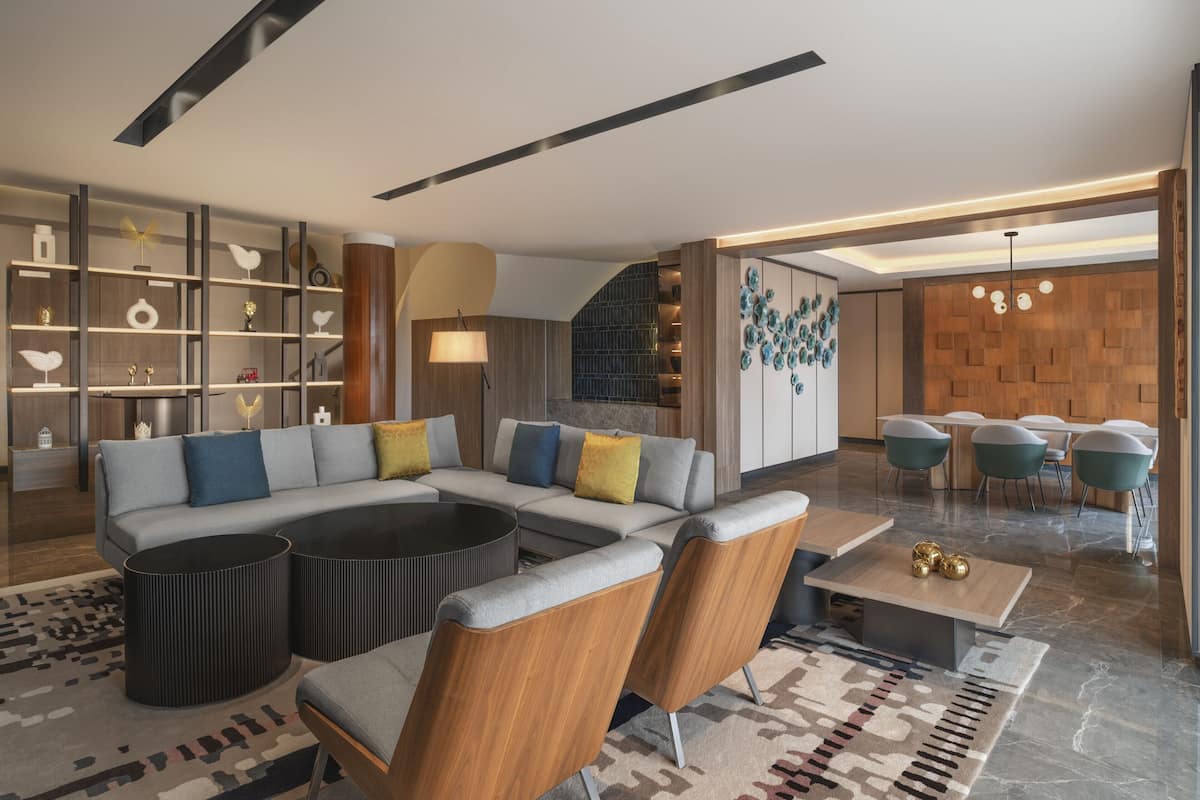 A modern living room with a sectional sofa, a coffee table, and a bookshelf.