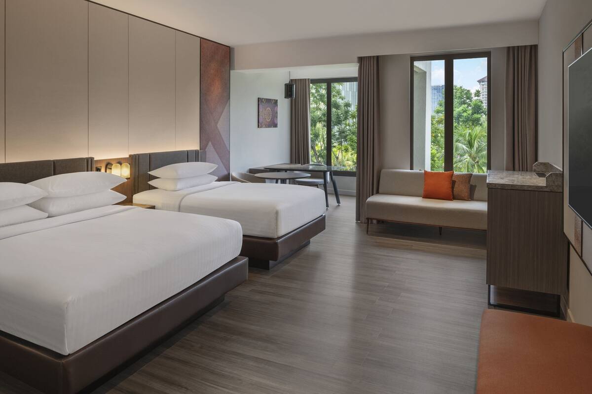 A hotel room with a large bed, a sofa, a small table, and a TV.