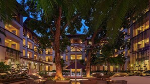 Un hotel de varios pisos con zonas de estar al aire libre, una fuente central y un pabellón cubierto.