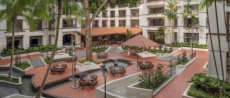 A courtyard with outdoor seating, palm trees, and a central water feature.