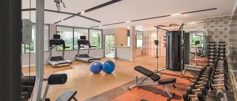 A gym with cardio equipment, weightlifting stations, and exercise balls.