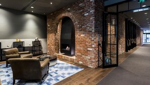 A modern lounge area with a brick fireplace, leather sofas, and a checkered rug. - WRAP on Southbank (Southbank)
