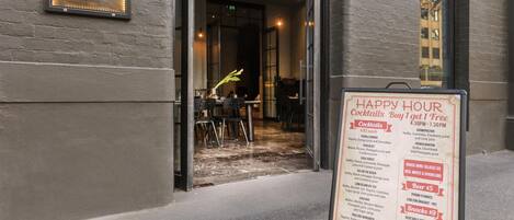Ein Restaurant-Eingang mit einem Schild, das Happy-Hour-Angebote auflistet.