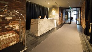 A reception area with a marble counter, a brick wall, and a modern chandelier. - WRAP on Southbank (Southbank)