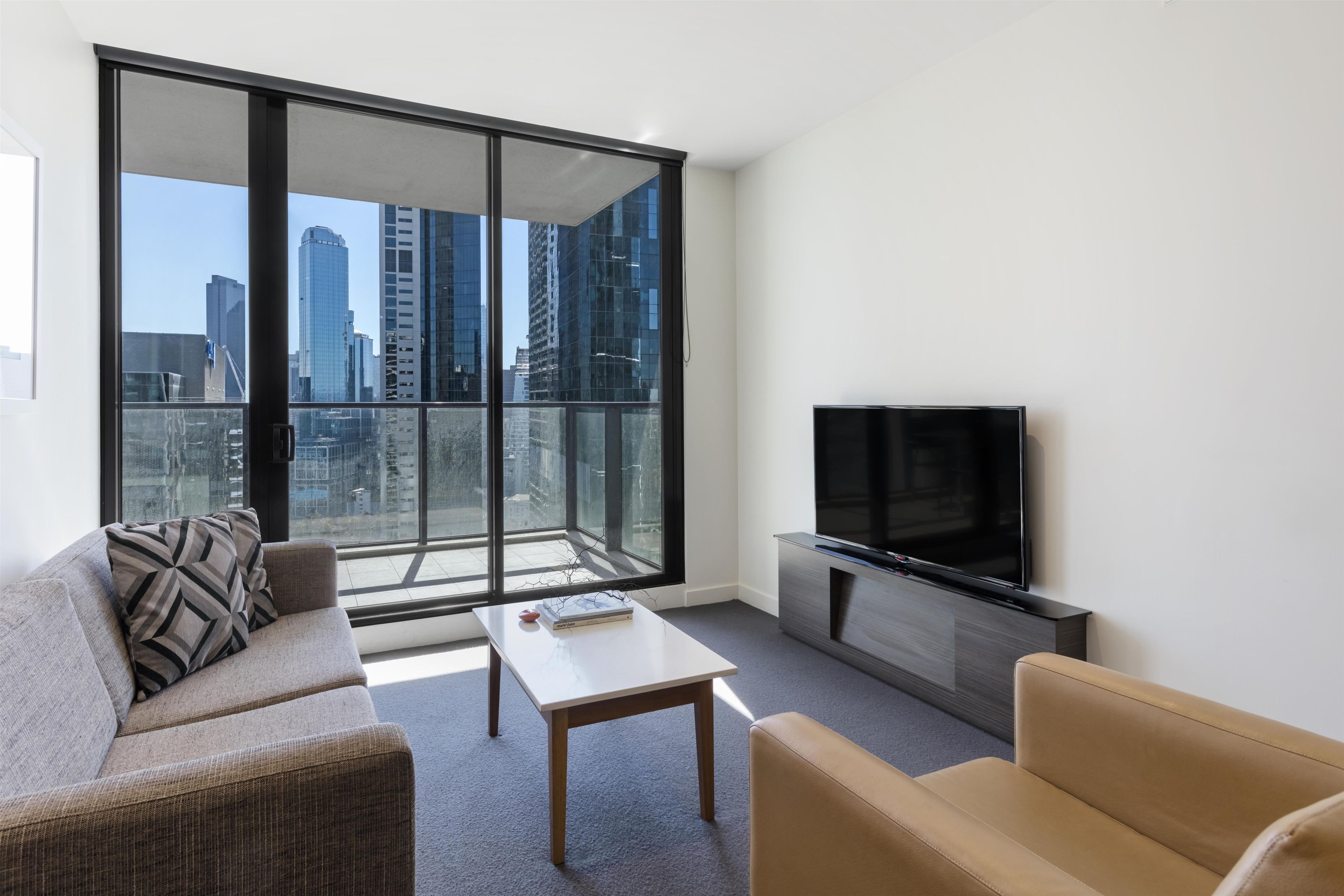 Ein modernes Wohnzimmer mit großem Fenster, Flachbildfernseher und einer Couch.