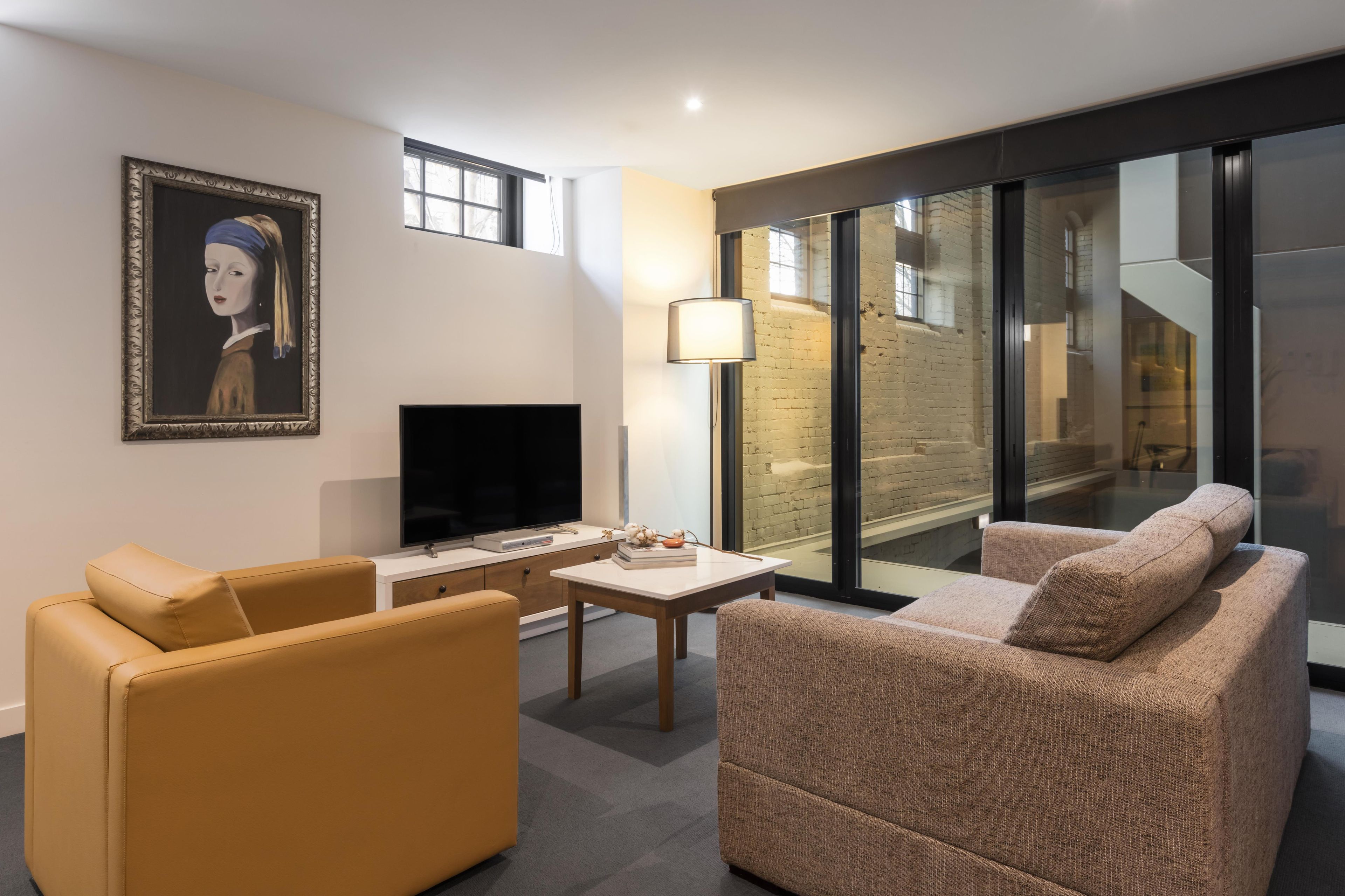 A modern living room with a sofa, a coffee table, a TV, and a painting on the wall.