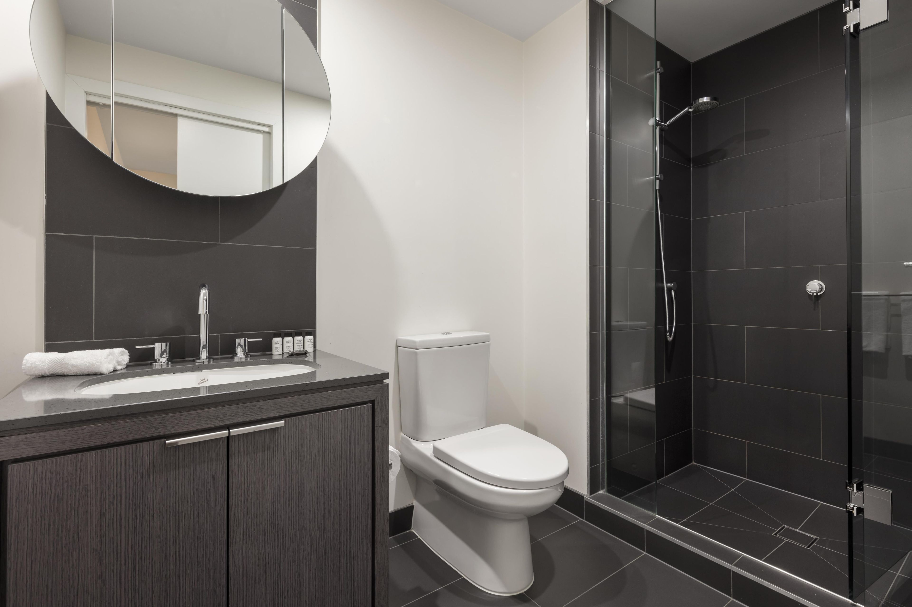 A modern bathroom with a sink, toilet, and glass-enclosed shower.
