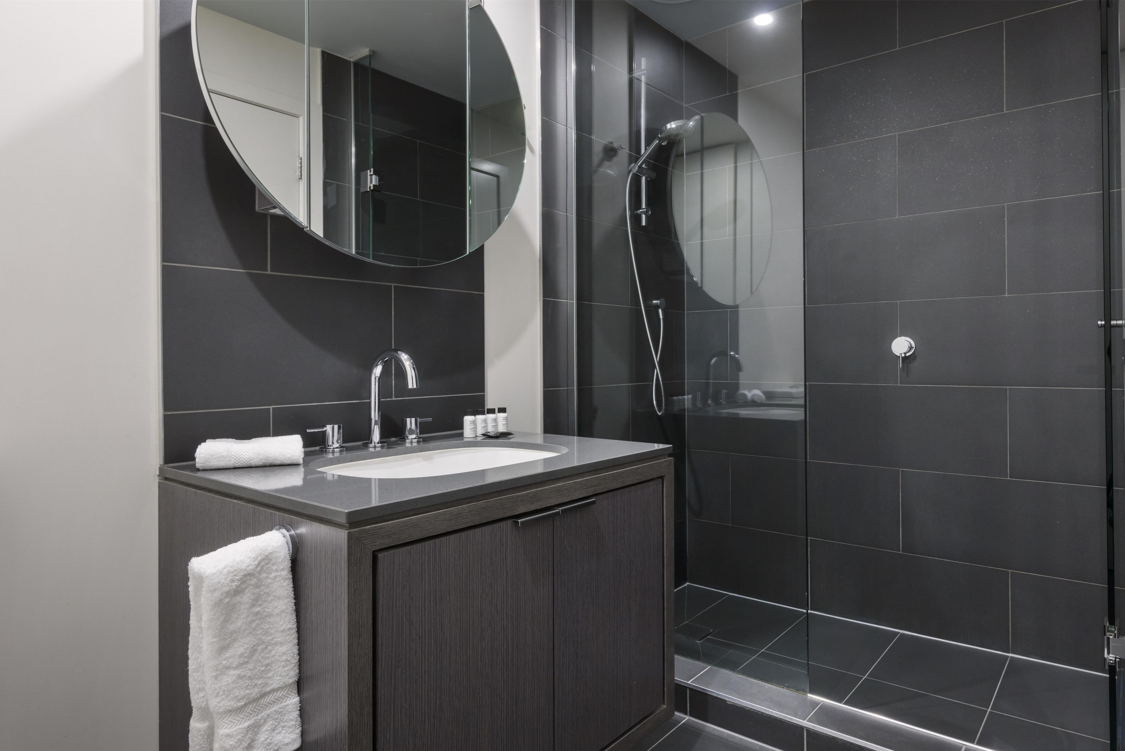 A modern bathroom with a sink, mirror, and shower.