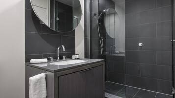 A modern bathroom with a sink, mirror, and shower.