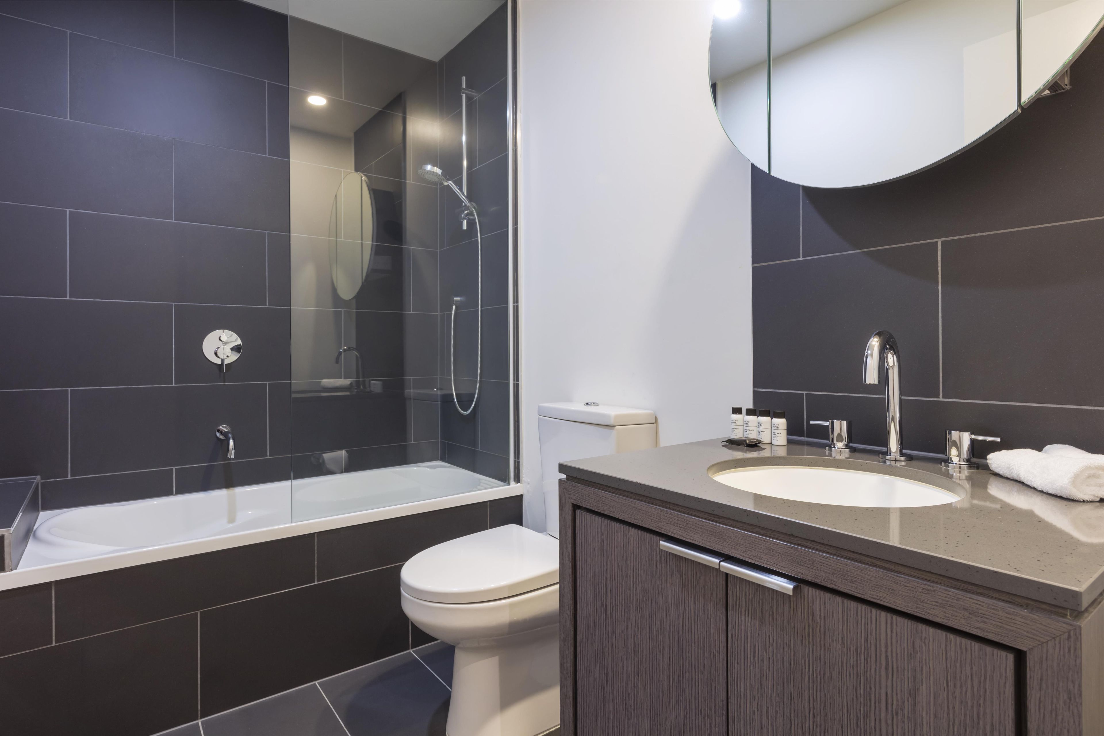 A modern bathroom with a bathtub, toilet, and vanity with a sink.
