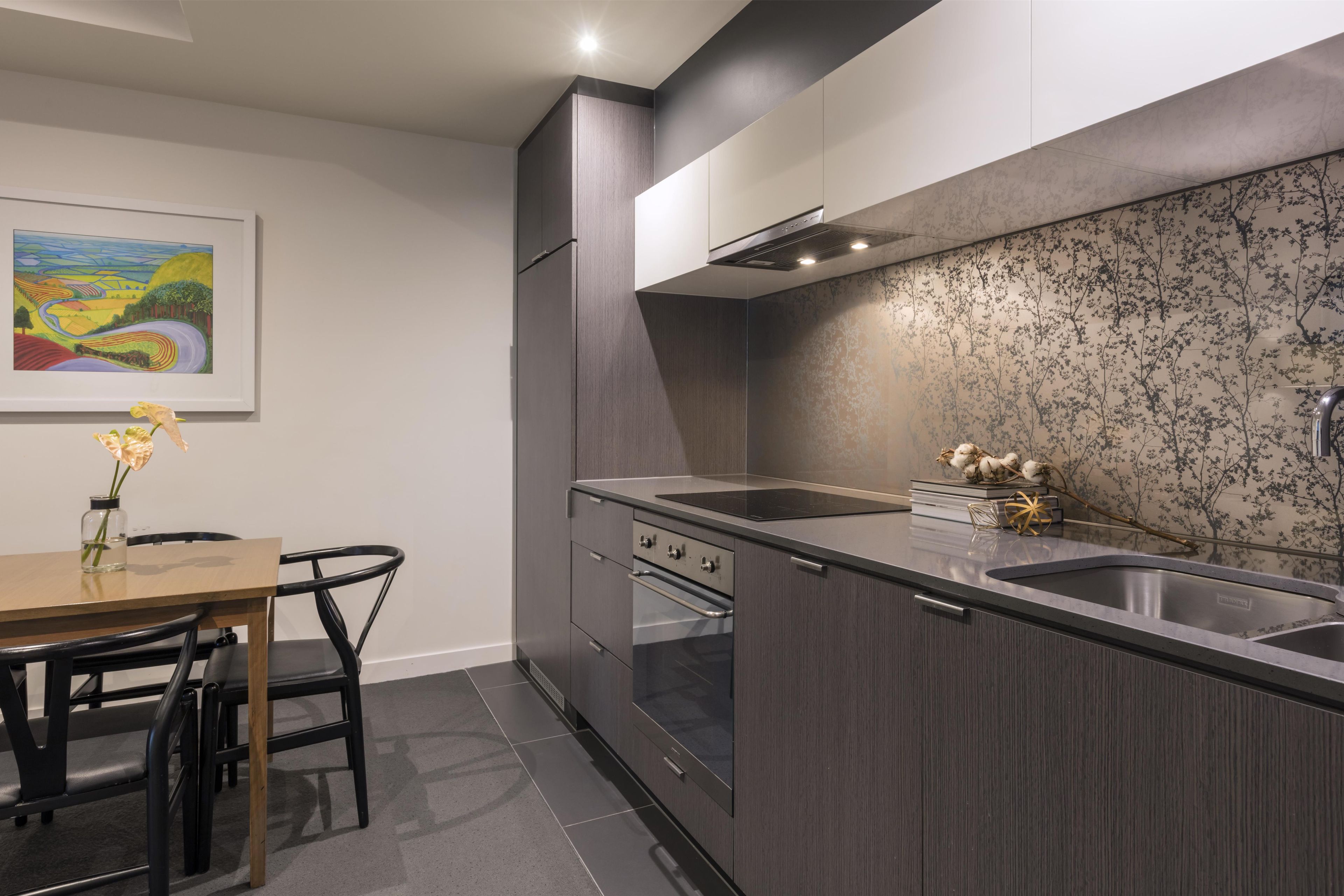 A modern kitchen with dark cabinetry, a built-in oven, and a countertop with a sink.
