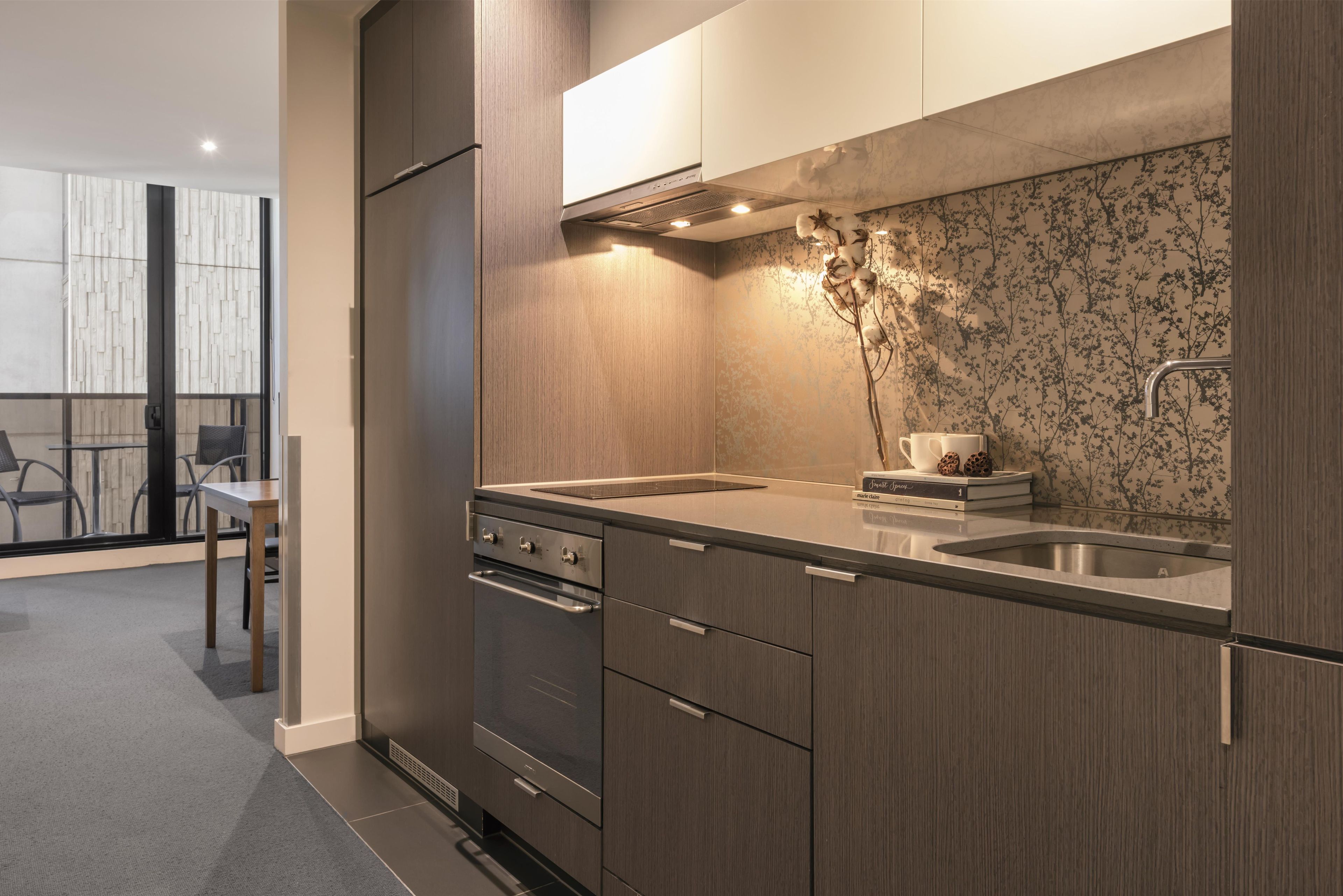 A modern kitchen with a double sink, stainless steel appliances, and a decorative backsplash.