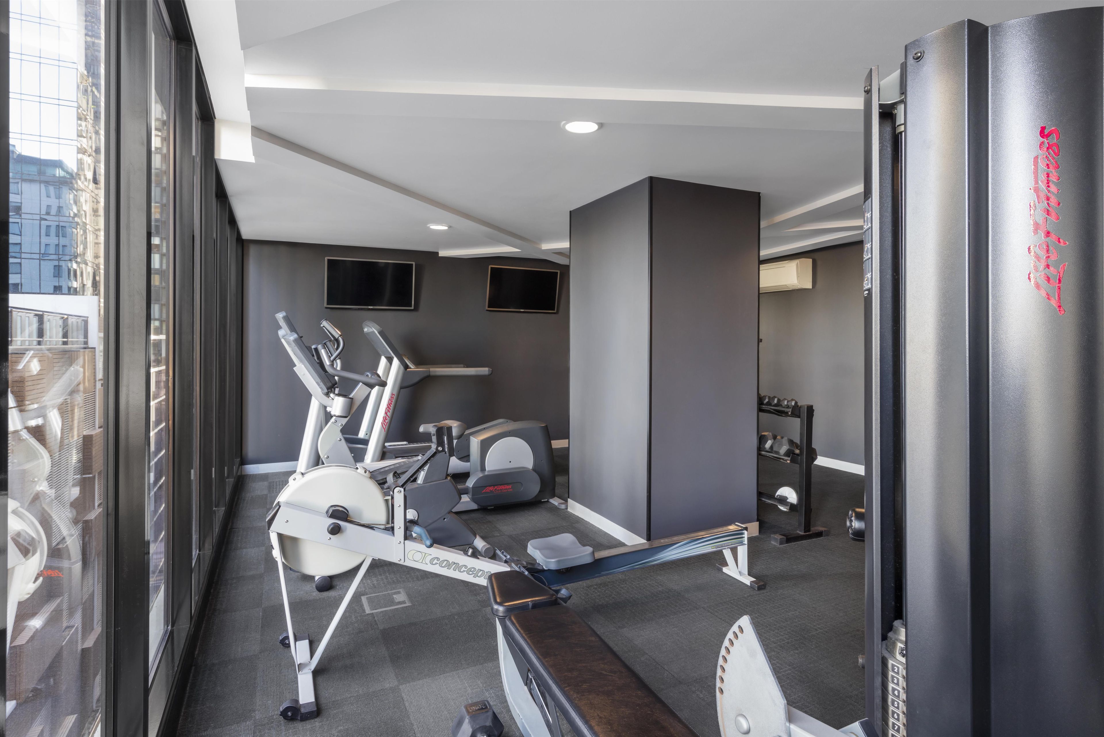 A modern gym with stationary bikes, treadmills, and weight machines.