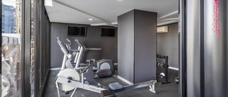 A modern gym with stationary bikes, treadmills, and weight machines.